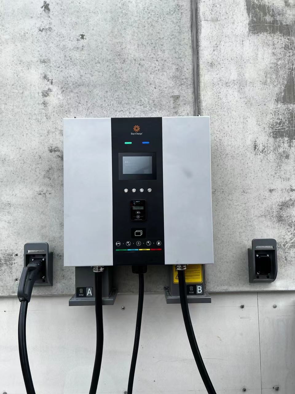 Installed charging equipment with connectors arranged beside the unit.