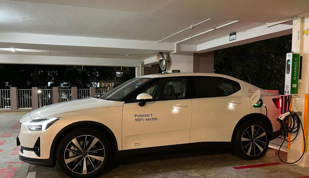 A passenger EV parked beside a charging point in a covered car park.