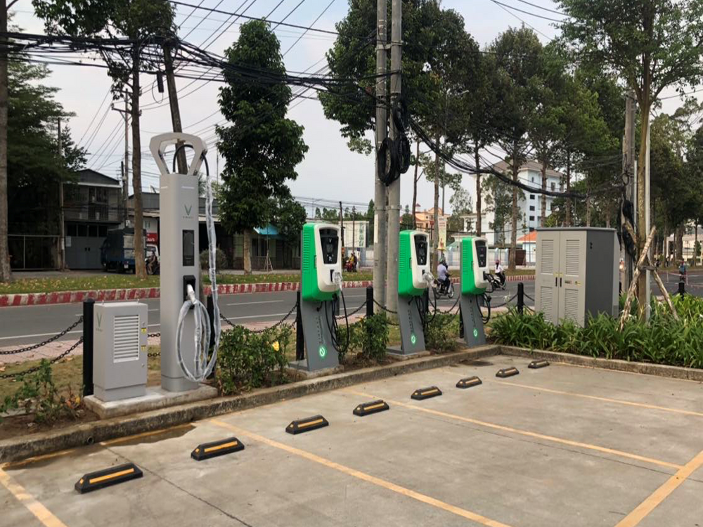 A row of EV charging points at a tree-lined parking location.