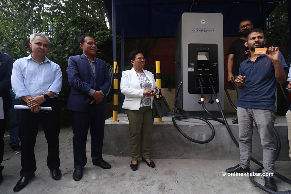 Visitors gathered beside installed EV charging equipment.